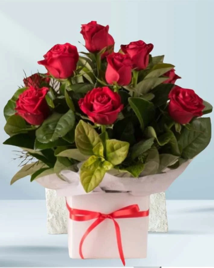 Bouquet of red roses with a white box and red ribbon on a light blue background