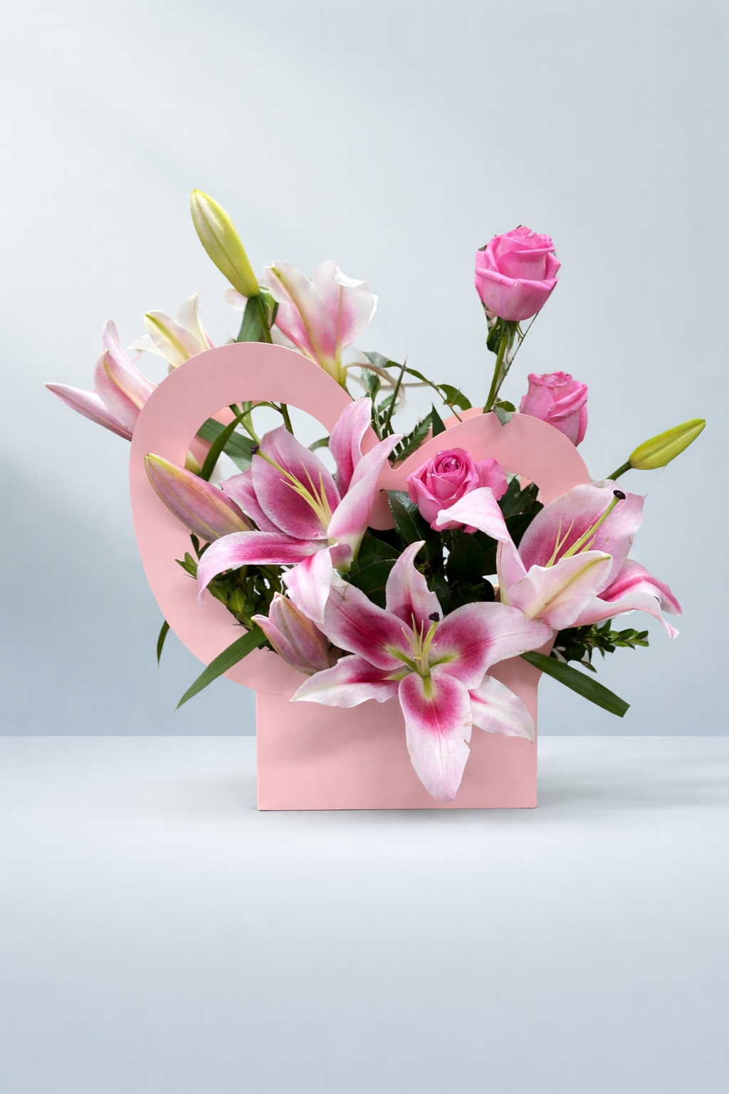 Pink oriental lilies and roses arranged in a pastel pink heart-shaped box by Emflowerment Florist Croydon, available for same-day flower delivery.