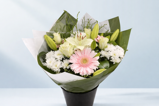 Bouquet of flowers wrapped in green paper with a light blue background