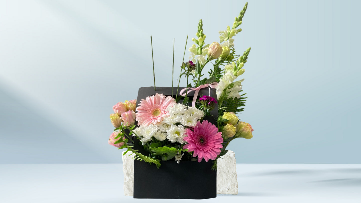 Floral arrangement in a black box on a light blue background