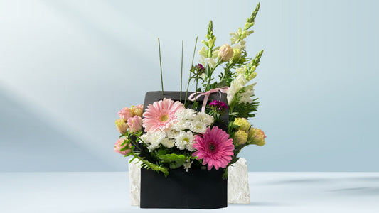 Floral arrangement in a black box on a light blue background