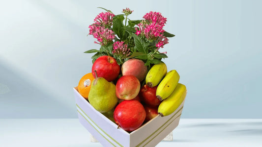 Fruit and flower arrangement in a box on a light blue background