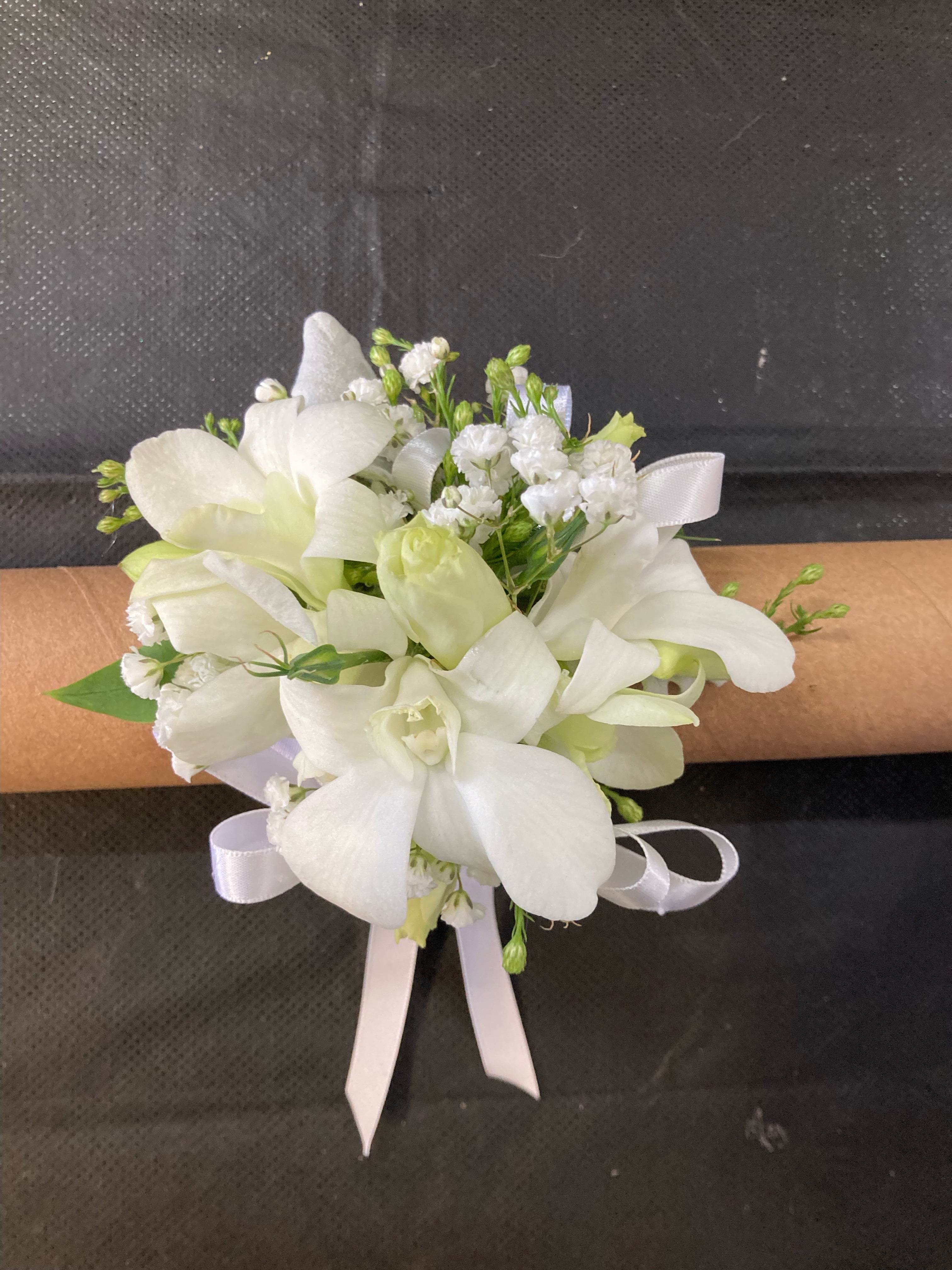Fresh white orchid corsage with pink-edged petals and baby’s breath accents.