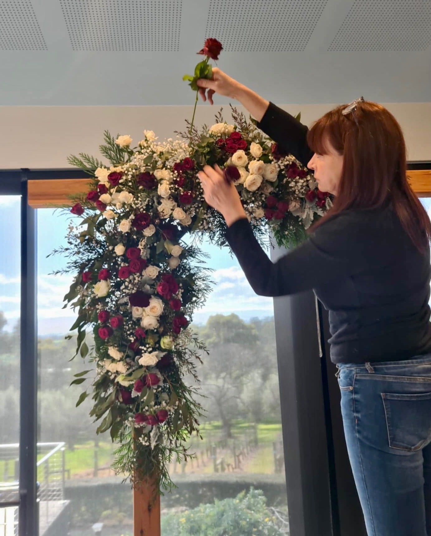 Melissa from Emflowerment arranging flowers in a decorative setup indoors for a Wedding