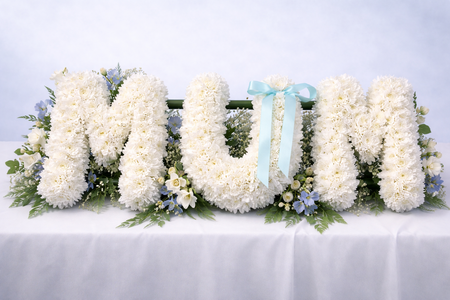 White “MUM” funeral floral tribute with chrysanthemums, roses and blue flowers, available for memorial and funeral delivery in Croydon by Emflowerment.