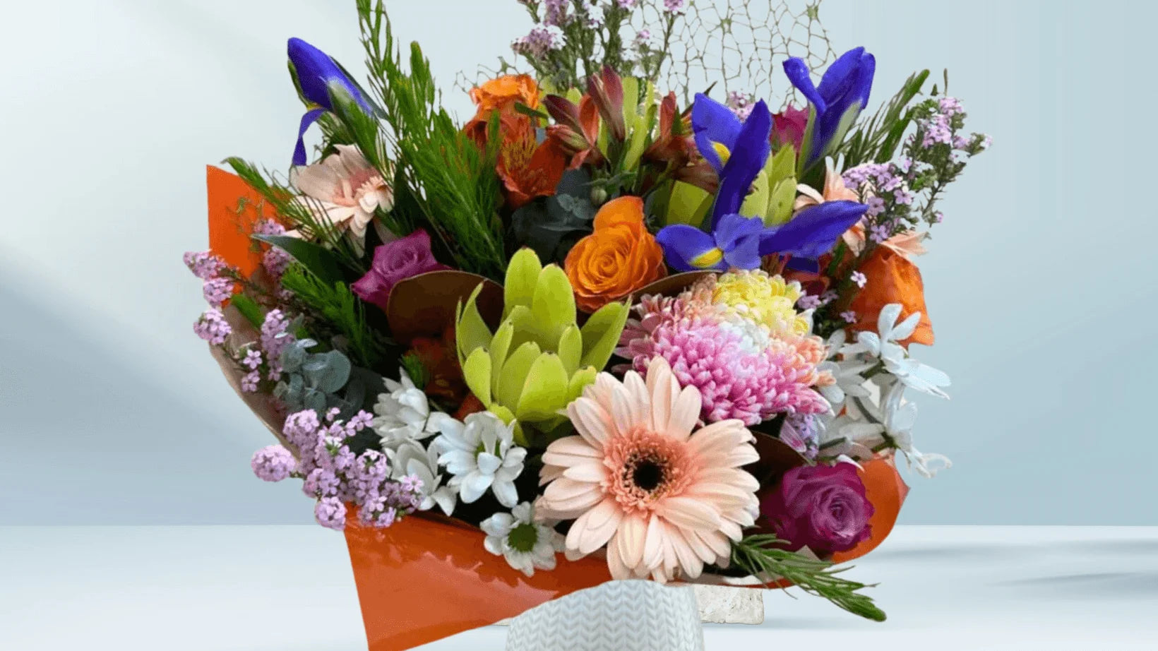 Colorful bouquet of native flowers on a light blue background by Emflowerment Croydon for same day delivery
