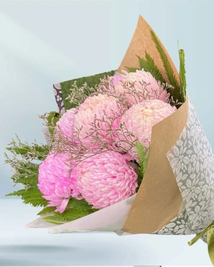 Bouquet of pink flowers wrapped in brown paper with a light blue background