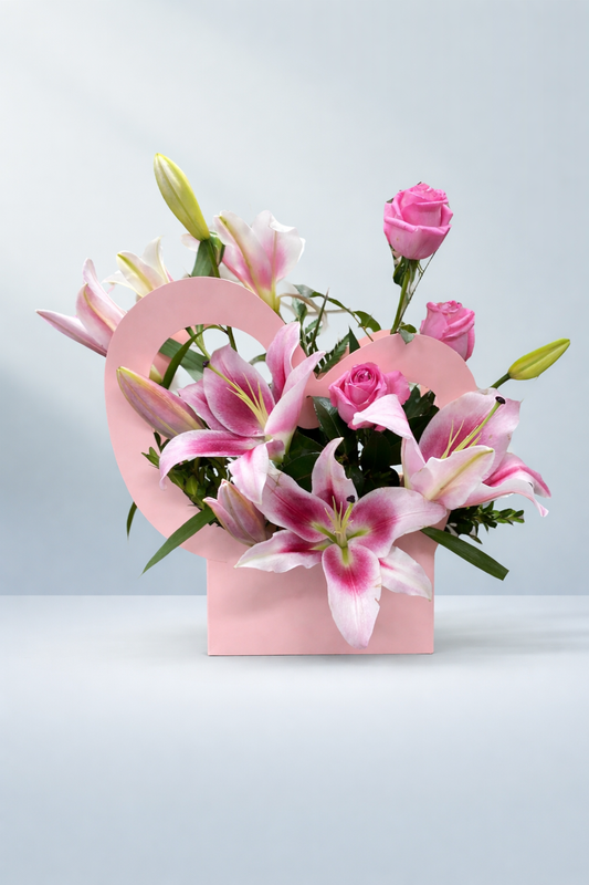 Pink oriental lilies and roses arranged in a pastel pink heart-shaped box by Emflowerment Florist Croydon, available for same-day flower delivery.