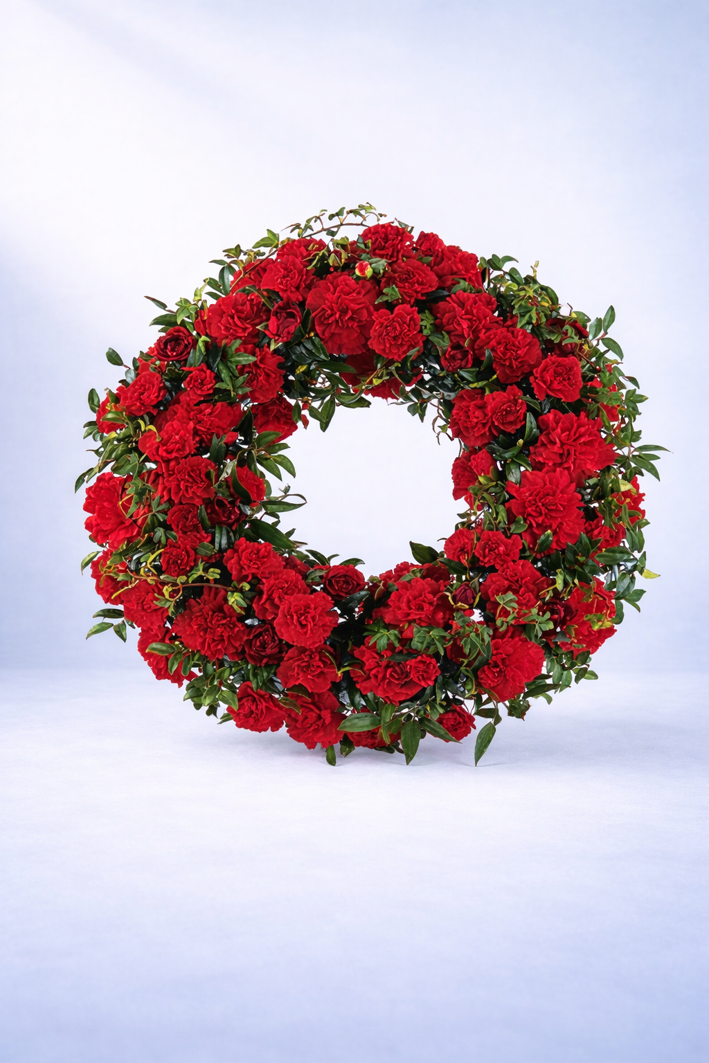 Floral wreath with red flowers and green leaves on a light blue background