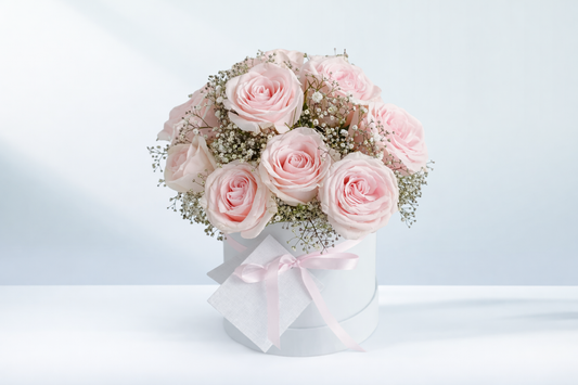 Valentine’s Day arrangement of 12 pink roses with baby’s breath in a white hatbox, approximately 40cm in length.