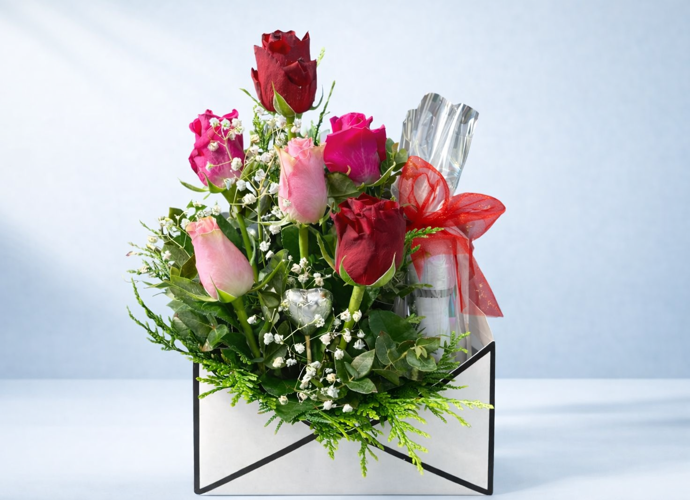 Bouquet of red, pink, and green flowers with a bottle of wine on a light gray background