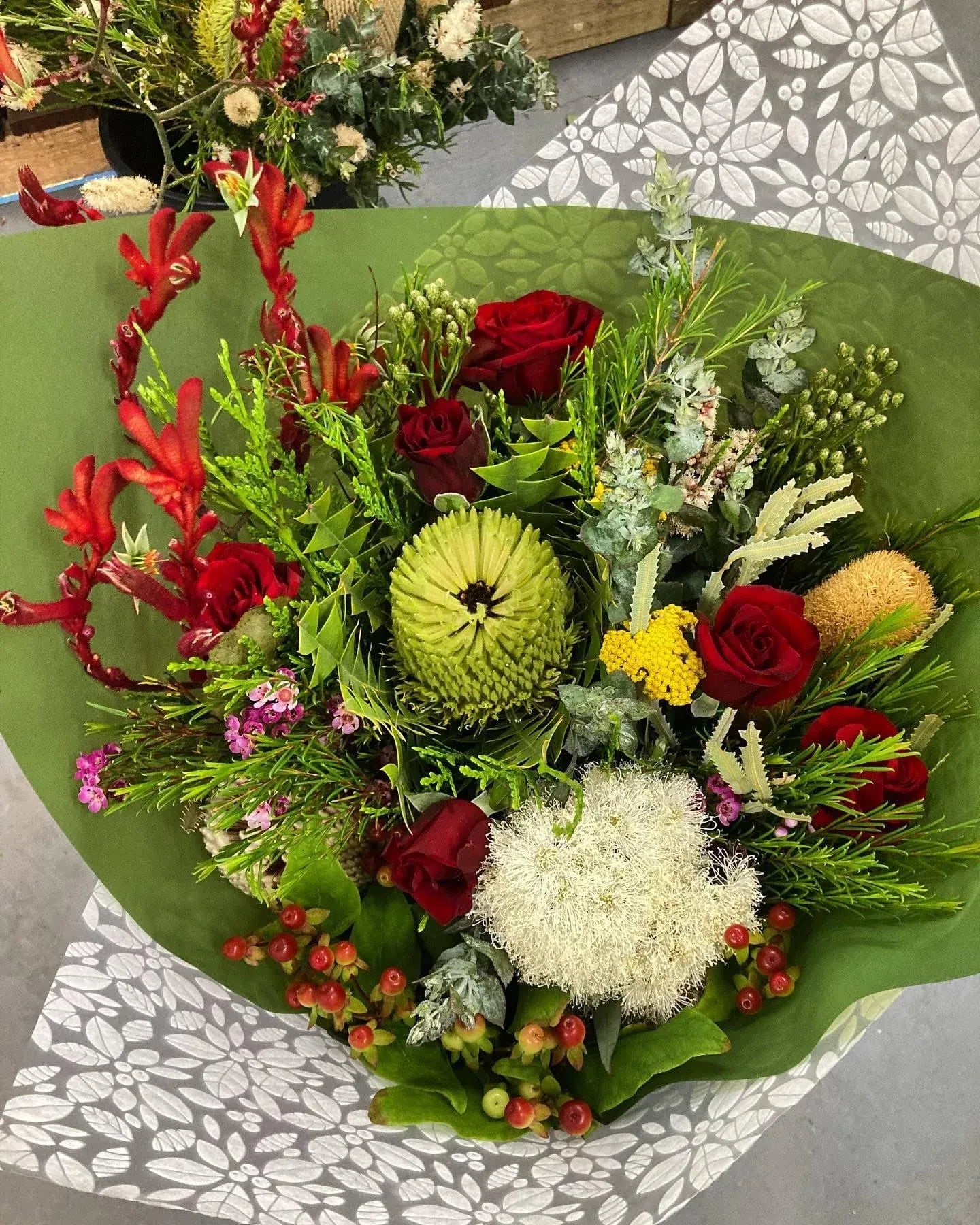 Bouquet of flowers with red, green, and yellow colors on a patterned surface.