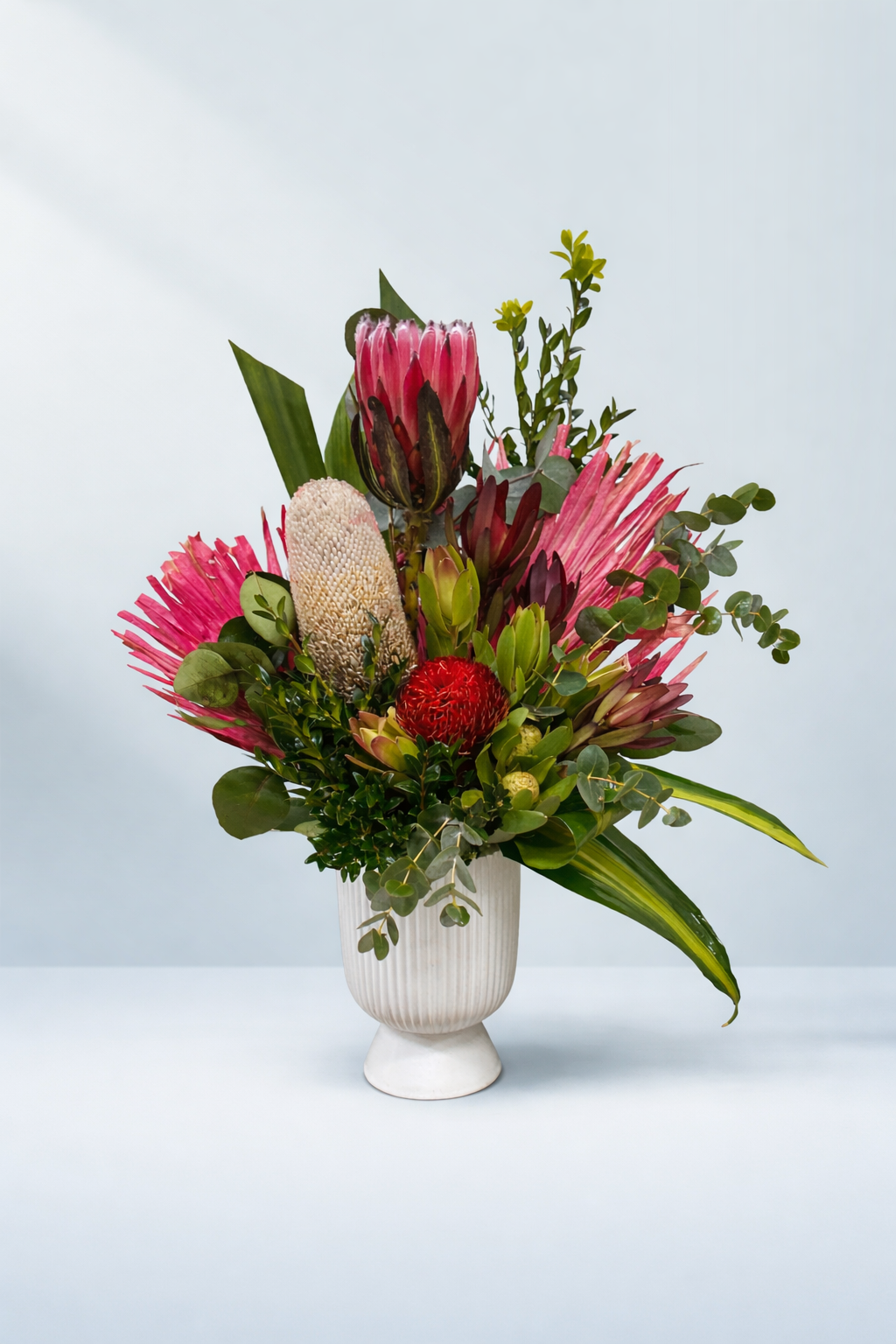 Floral arrangement with pink and red flowers in a white vase on a light gray background by Emflowerment Croydon for same day delivery